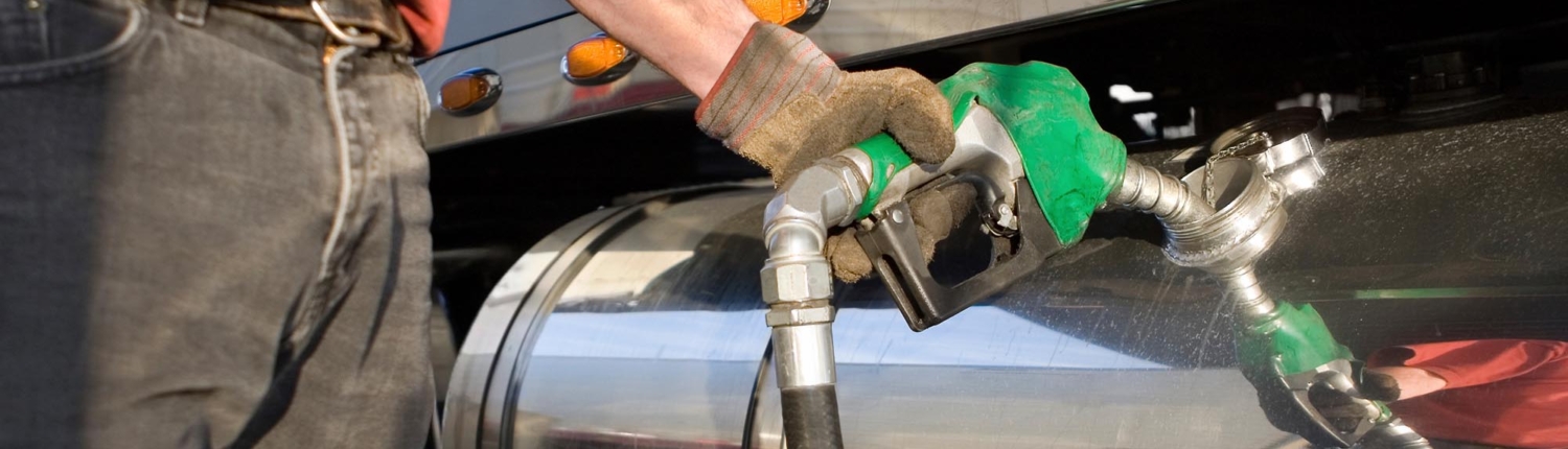 Side view of a truck driver filling up the gas tank