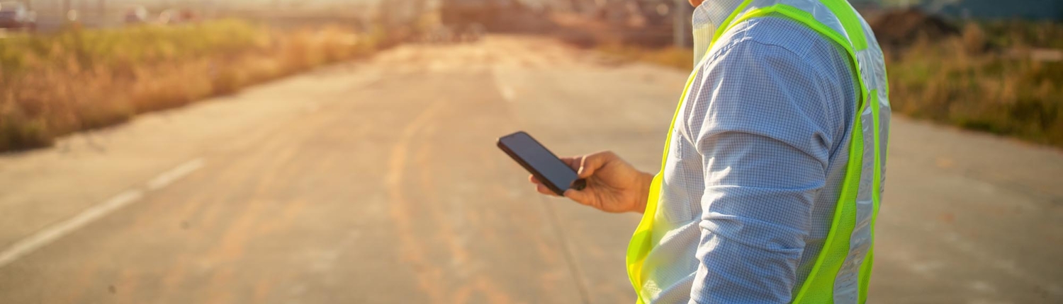Side view of a man in yellow reflective vest using his cell phone