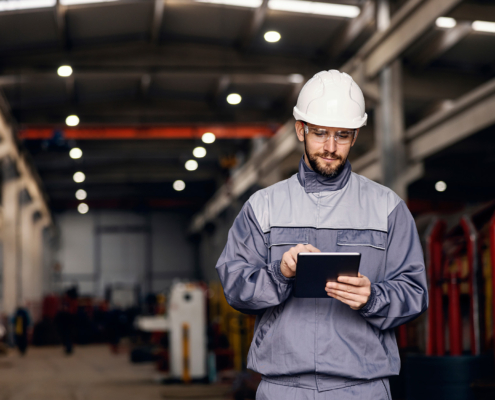 Focused heavy industry worker uses tablet in facility