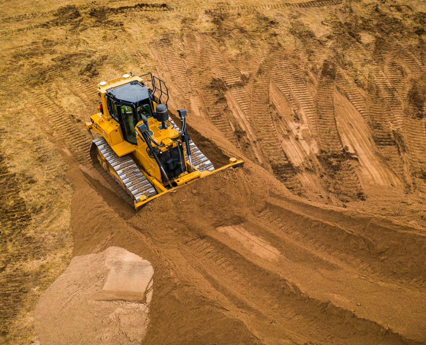 A bull dozer pushes sand into a large pile