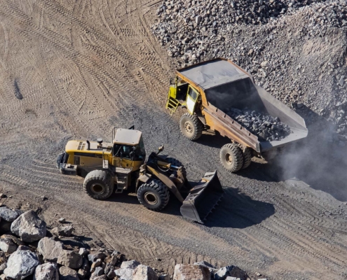 Excavator loading dumper truck on mining site stock photo