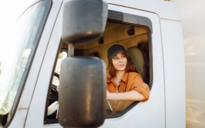 A Young Woman Sits In The Cab Of A Cargo Truck