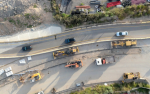Aerial View Of Road Construction Site With Heavy Machinery, Trucks And Workers