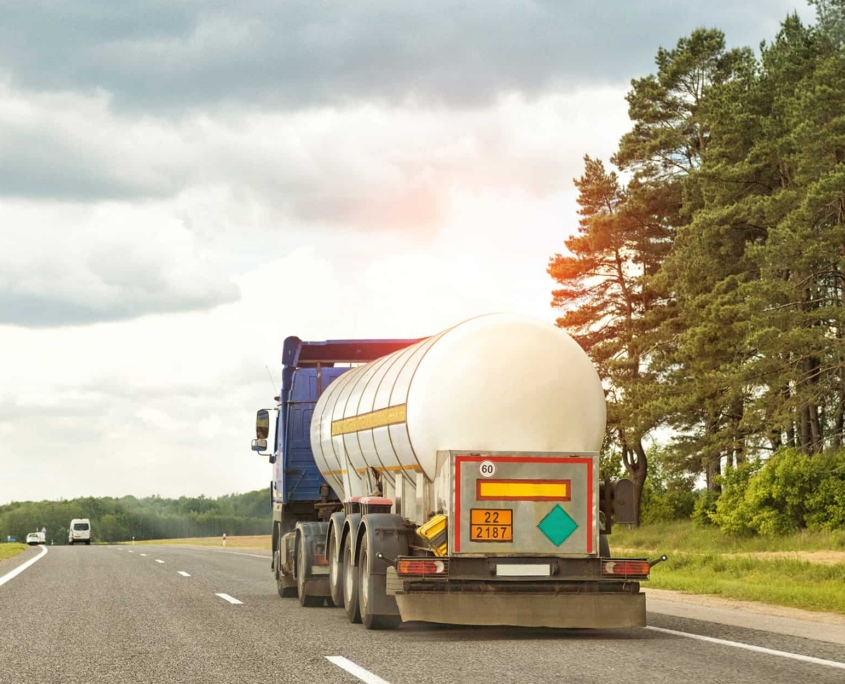 Back View Of A Semitruck Driving Down The Road With Cloudy Sky In The Background