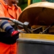 Builder In Safety Gloves Filling Excavator With Diesel Fuel On Building Site