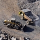 Excavator Loading Dumper Truck On Mining Site Stock Photo