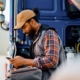 Side View Of A Truck Driver Texting While Standing Near His Semitruck