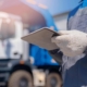 Worker Checking Tablet Infront Of Trucks
